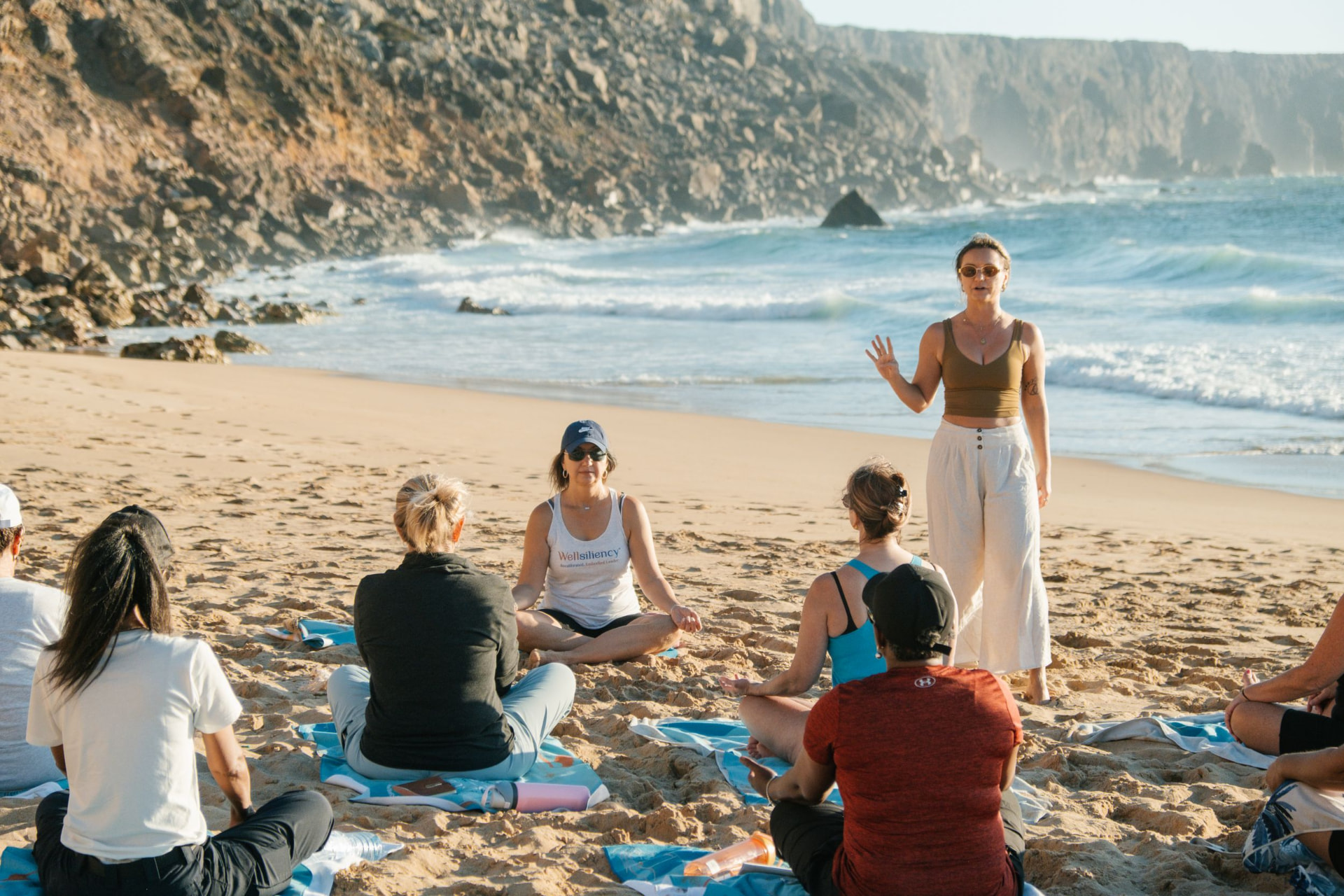 Izabella leading a seated group on a beach in the Algarve