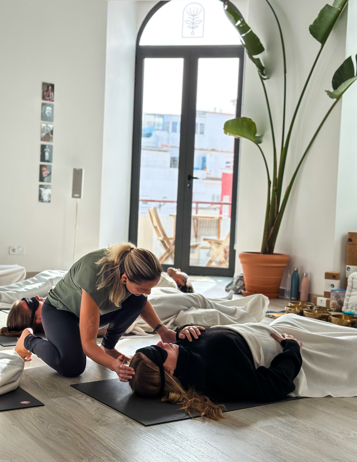Izabella tending a participant resting on a mat during a breathwork session in a sunlit studio
