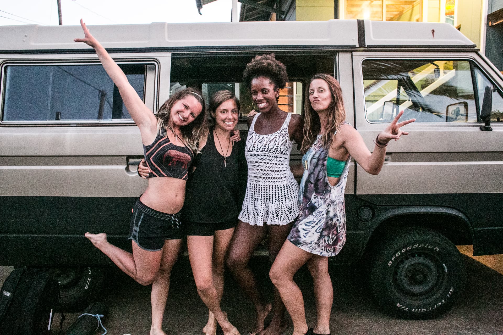 Izabella and three friends standing close together, laughing, in front of a camper van in Maui